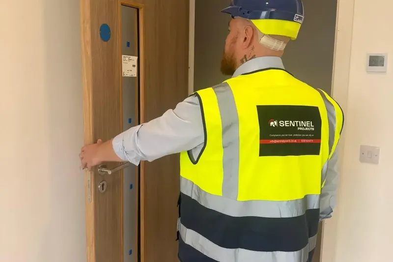 Sentinel Projects director in hi-vis checking an oak fire door on a residential site