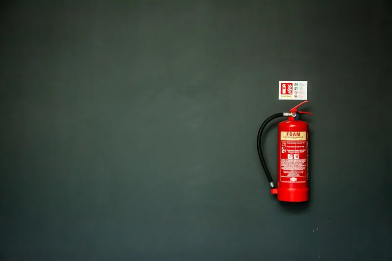 Close-up of a fire extinguisher pressure gauge and valve head during a service check