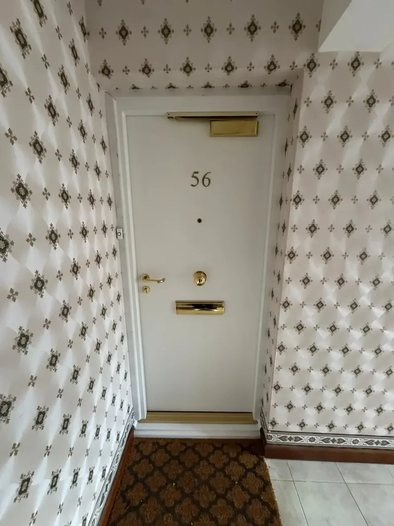 Newly installed white residential flat entrance fire door with brass ironmongery
