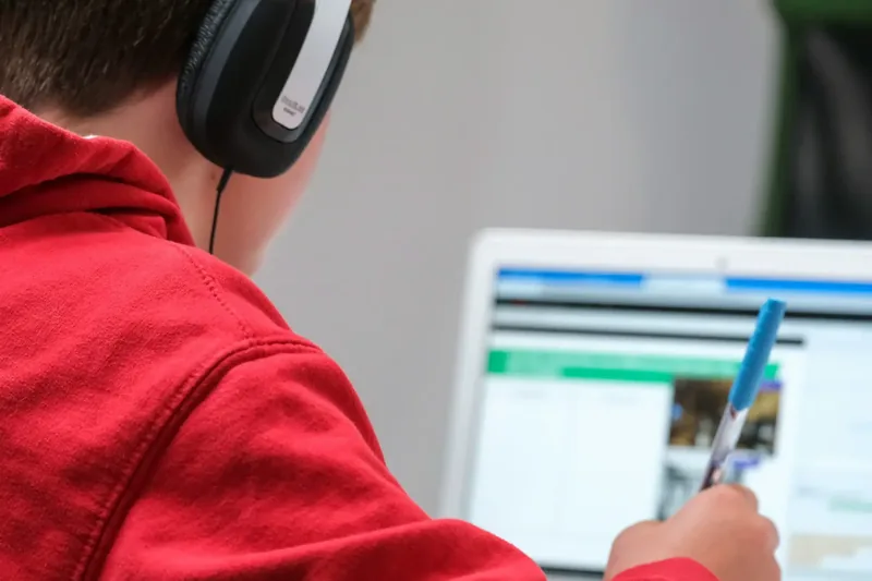 School pupil wearing headphones working at a laptop in a classroom