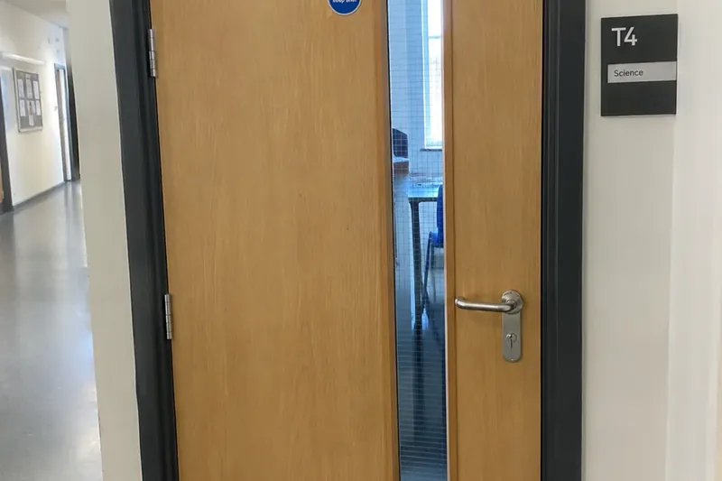 Oak FD30 fire door with vision panel, closer and keep shut sign in a school science corridor